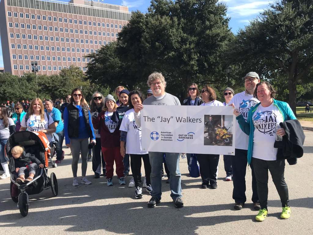 Members of The Jay Walkers walk together at the 201o Out of the Darkness Walk, carrying their team banner featuring the team name and a photo of Jay.